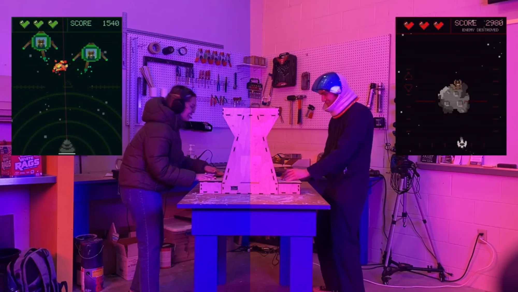 Still from Starlight Scrappers demo video. Two players dressed as astronauts play on either side of the gaming console
