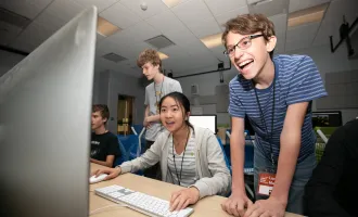 High school students smiling and laughing as they play an original video game created during SDCT's Summer Design Camp for teens