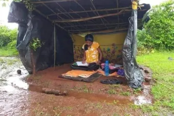 a young woman studying to be a doctor in a shed made of tarps with a dirt floor. It has been raining, so she is surrounded by mud