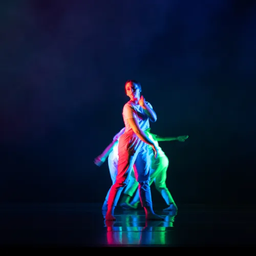 a dancer onstage at Evolution 2022 against a dark background, which makes the brightly colored lighting design stand out