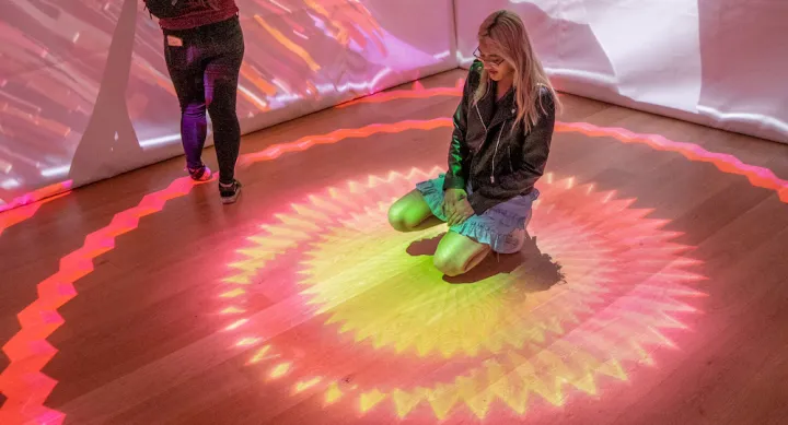 two Bee Cave BuzzFest attendees enjoy the Projection Mapped Cube inside the Hive Gallery, installed by UT Austin AET students